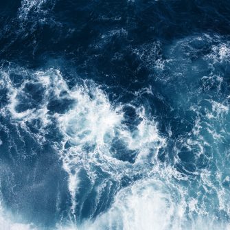 Top view on blue ocean waves and foam.