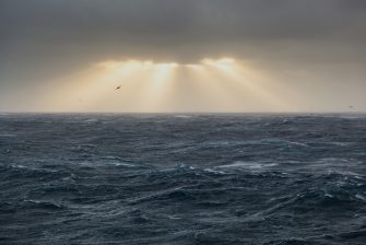 open ocean during a storm sun through clouds