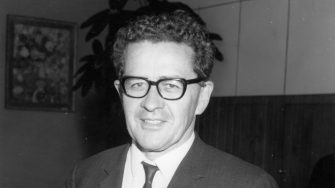 a black and white image of Hal Wootten wearing glasses