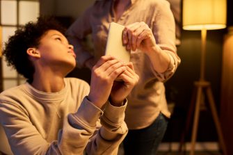 Teenager holding smartphone while parent taking device away during home conflict, illustrating screen time control. Useful for parenting, digital wellbeing, family rules
