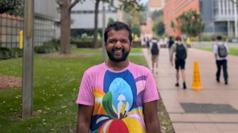 Portrait of Associate Professor Senthorun Raj, standing in the main walkway at UNSW in a bright multicolour t-shirt. 