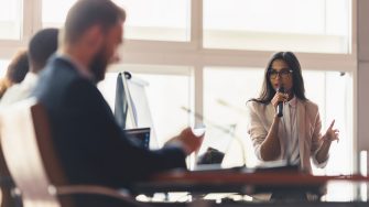 An Indian female presenter interacting with the committee members at a business presentation in the board room