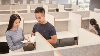 Students walking past bookcases at the law library UNSW.