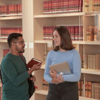 Students talking in front of bookcases in the UNSW law laibrary.