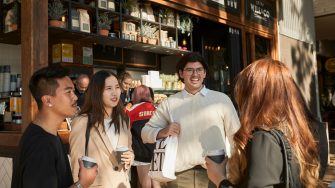 Students at standing with takeaway coffees at a coffee shop outdoors