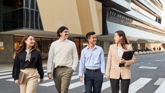 Group of law students walking behind law building, smiling and laughing, smart casual attire