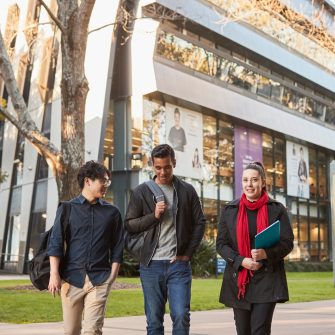 Three Law students walking on Main Wallkway with the Law Building in the background