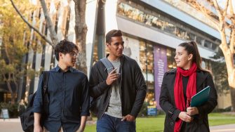 Three Law students walking on Main Wallkway with the Law Building in the background