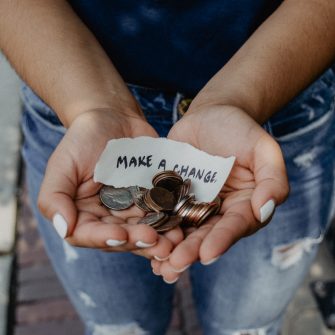 Person holding a handful of coins with a handwritten note that says 'make a change'.