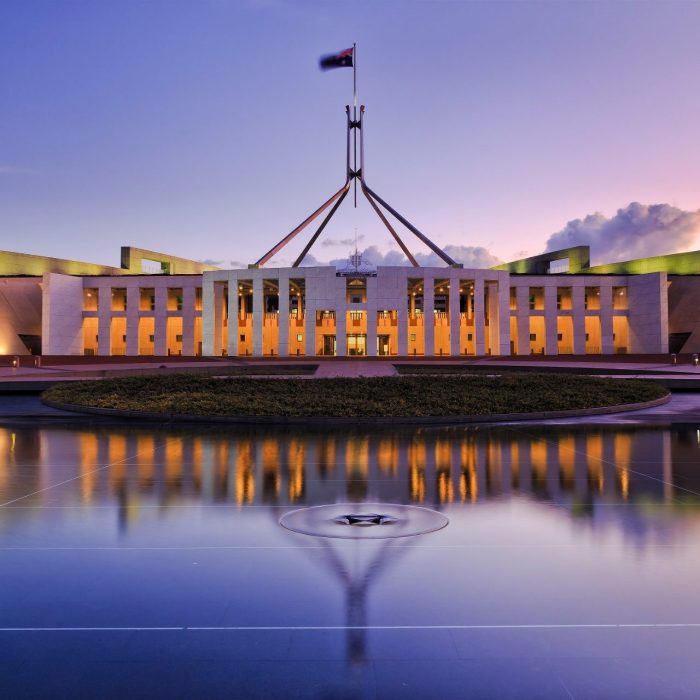 Australian Parliament House in Canberra at dusk, reflected in the water.