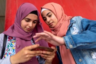 Two girls with Hijab are working with a phone