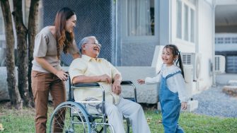 Disabled senior grandpa on wheelchair with grandchild and mother in park, Happy Asian multi generation family having fun together outdoors backyard, Grandpa elderly and little child smiling and laugh.