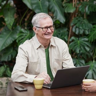 Elderly man on laptop outside smiling