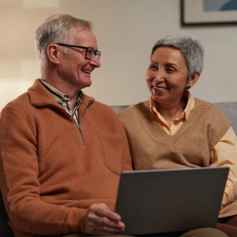 Elderly couple on laptop smiling 