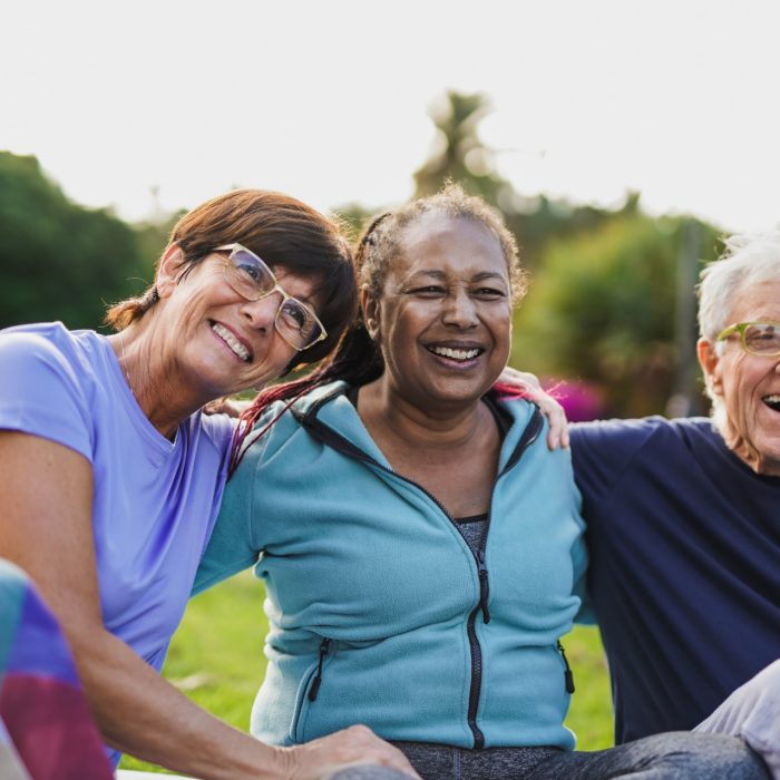 Happy elderly people having fun hugging each other outdoor after yoga lesson