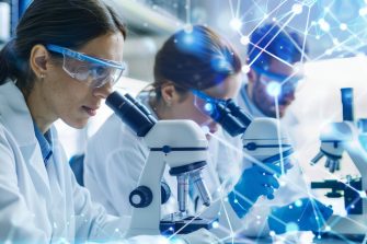 Researchers in a biotech lab examining interconnected cell samples under a microscope, with advanced equipment and DNA models, showcasing interconnected biotech advancements 