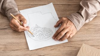 cropped view of retired man with alzheimer disease drawing human head and brain