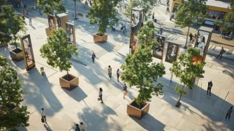 "Outdoor public space with large square planters containing trees, tall vertical digital screens displaying advertisements and images of people, and a few individuals walking or standing. A street with more people and buildings, including a food kiosk, is visible in the background. Sunlight casts shadows from the trees and planters onto the ground.