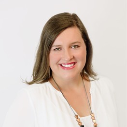 A woman in a white shirt looking into the camera smiling