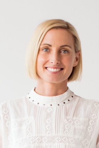 A woman in a white shirt looking into the camera smiling