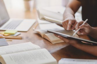 Close-up view of university students discussing their group project while using tablet 