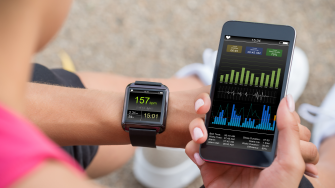 Female Runner Looking At Her Mobile And Smart Watch Heart Rate Monitor