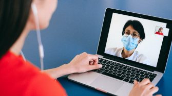 Woman with face mask on laptop screen