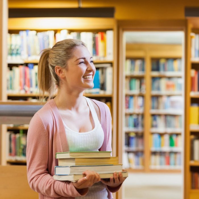 Couple smiling at each other at the library while holding books