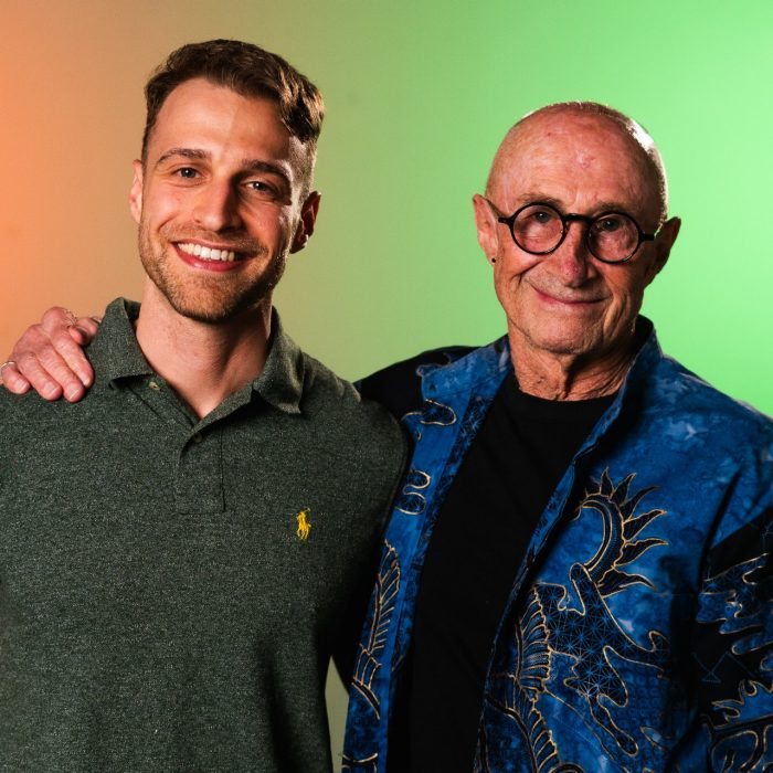 Two people smile towards the camera, arms around each other.