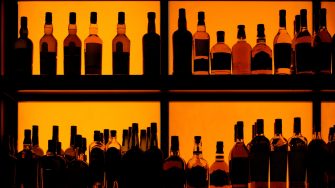 Bottles sitting on shelf in a bar, back lit
