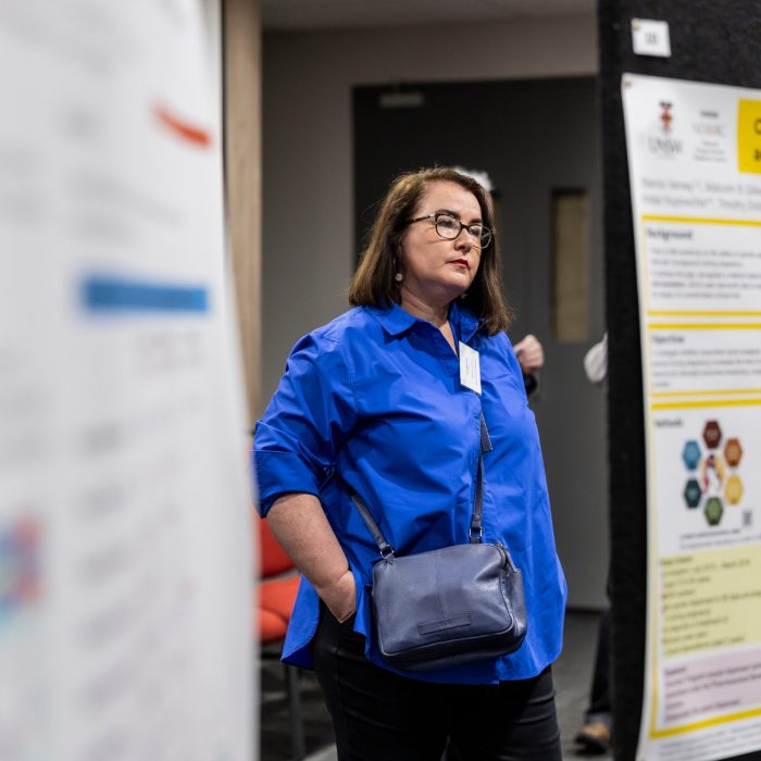 Woman standing in between posters on display at research symposium