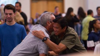 Men hugging at community meeting