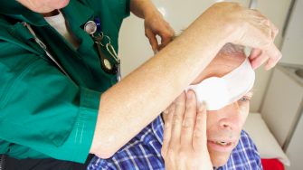 Paramedic nurse bandaging a patient's eye after injury- drops applied bandages being wrapped.