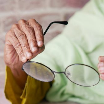 Older person holding their glasses