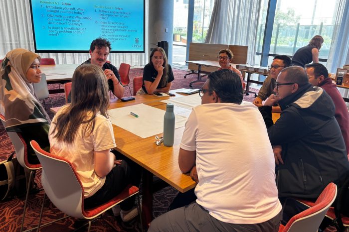 Participants in the Equity at the Heart workshop sit around a square table listening to someone speak