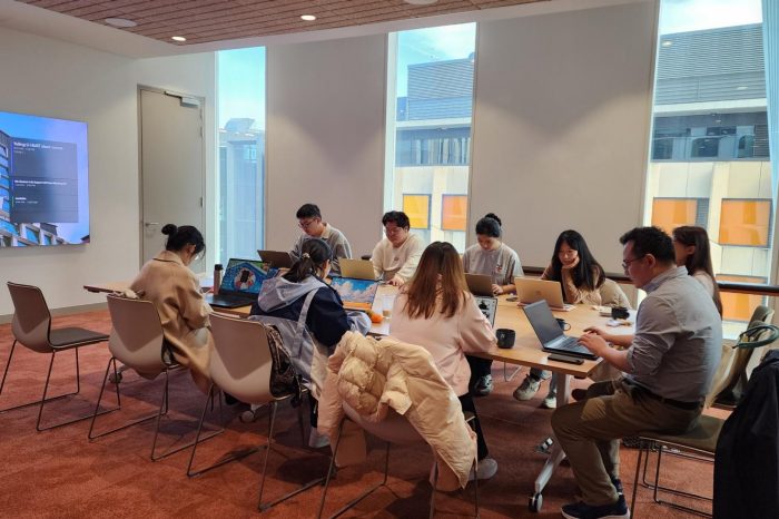 The visitors from HUST sit around a table looking at laptops