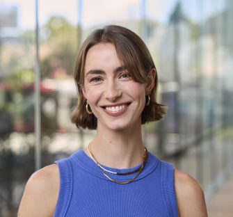 Anneke de Vries-Egan stands in front of a blurred background, smiling