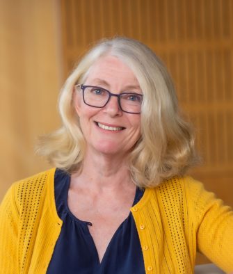 Lara Harvey smiles at camera in front of a blurred, neutral background