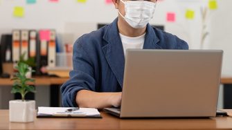 student at laptop with mask on