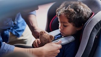 Shot of a father fastening his little son safely in a car seat