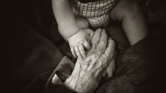 elderly and baby hands touching