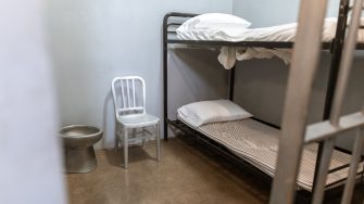 A Bunk Bed With Striped Foam Mattress in a Prison Cell