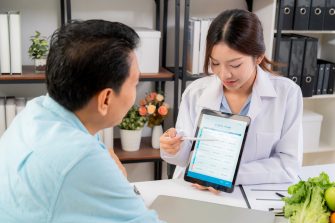 Medic using tablet to explain something to patient using AI on tablet.