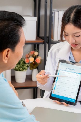 Medic using tablet to explain something to patient using AI on tablet.