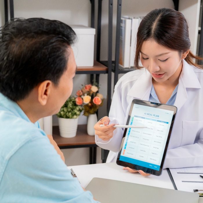 Medic using tablet to explain something to patient using AI on tablet.
