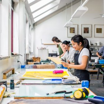 Students work on projects in an art and design workshop environment