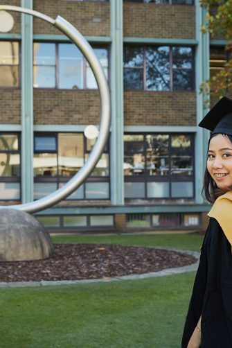 A graduate in gown on UNSW Library Lawn