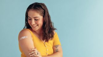 Woman looking at her arm with band-aid after receiving vaccine dose. 