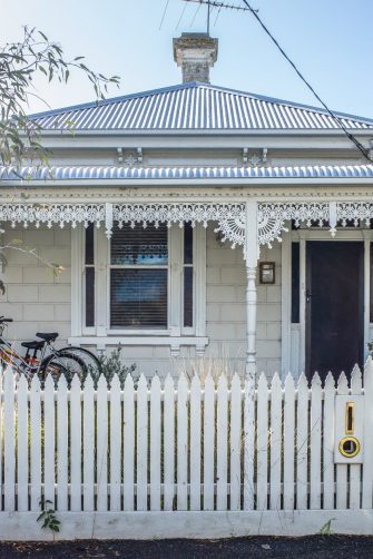 Corrugated iron house in Melbourne with a white fence in front of it