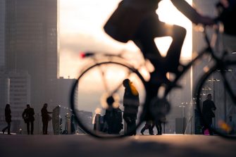Morning image of businessman on bicycle passing skyline of La Defense business district in Paris, France.